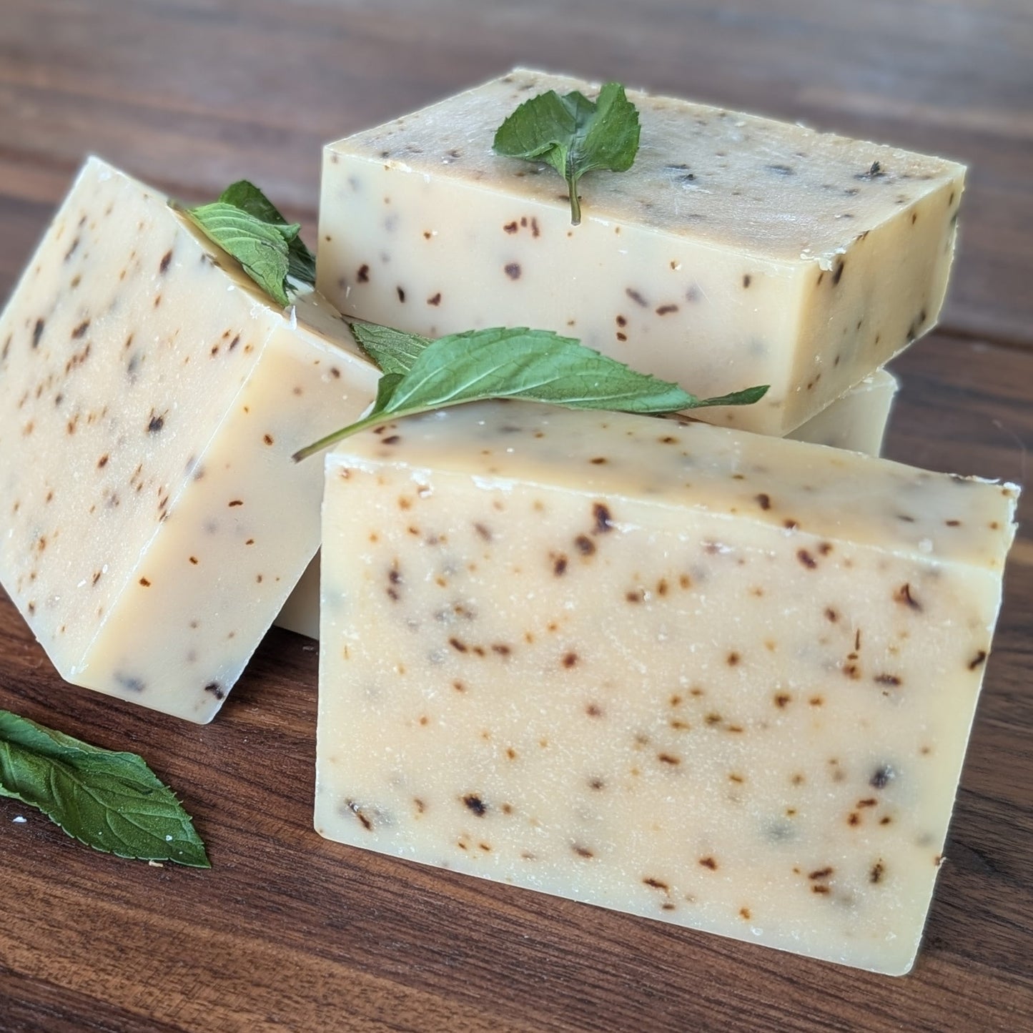 Bloom 'n Goat Rosemary Mint goat milk soap bars with homegrown fresh mint leaves on a walnut wood background