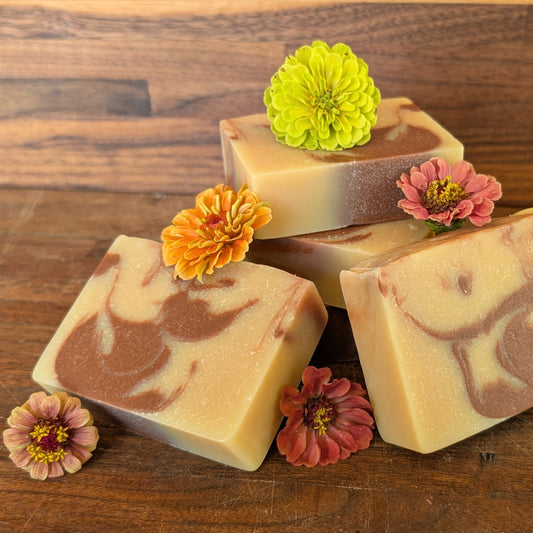 Bloom 'n Goat Citrus Bloom goat milk soap bars with natural marbled patterns and citrus zinnias on a wooden surface