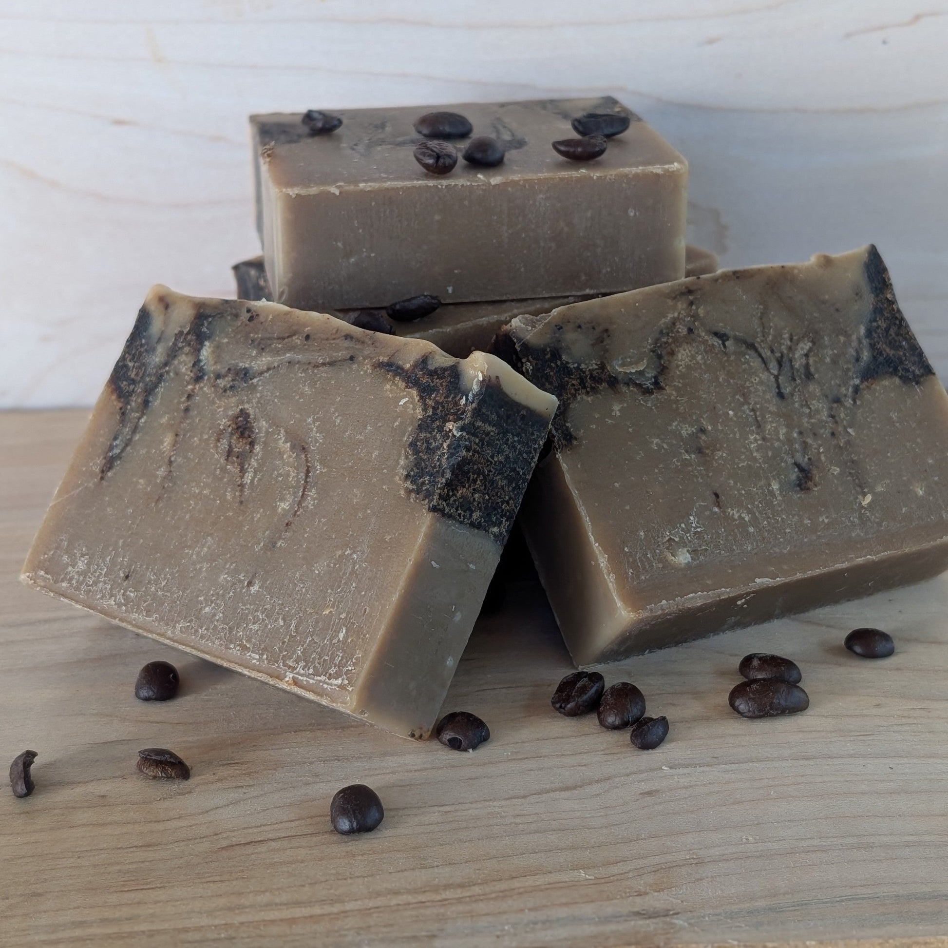Bloom 'n Goat Coffee Swirl goat milk soap bars for odor removal displayed with whole coffee beans on maple wood