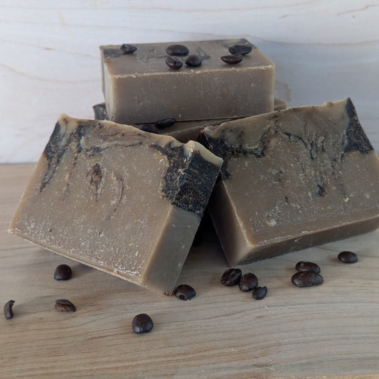 Bloom 'n Goat Coffee Swirl goat milk soap bars for odor removal displayed with whole coffee beans on maple wood