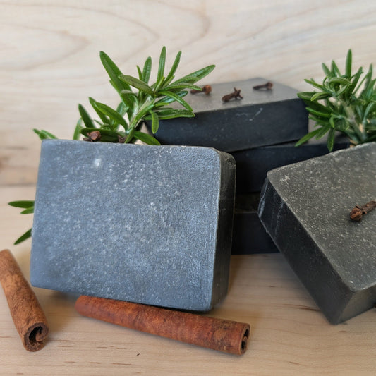 Bloom 'n Goat Firefighter's Detox activated charcoal goat milk soap bars with rosemary cinnamon and clove on a maple wood background